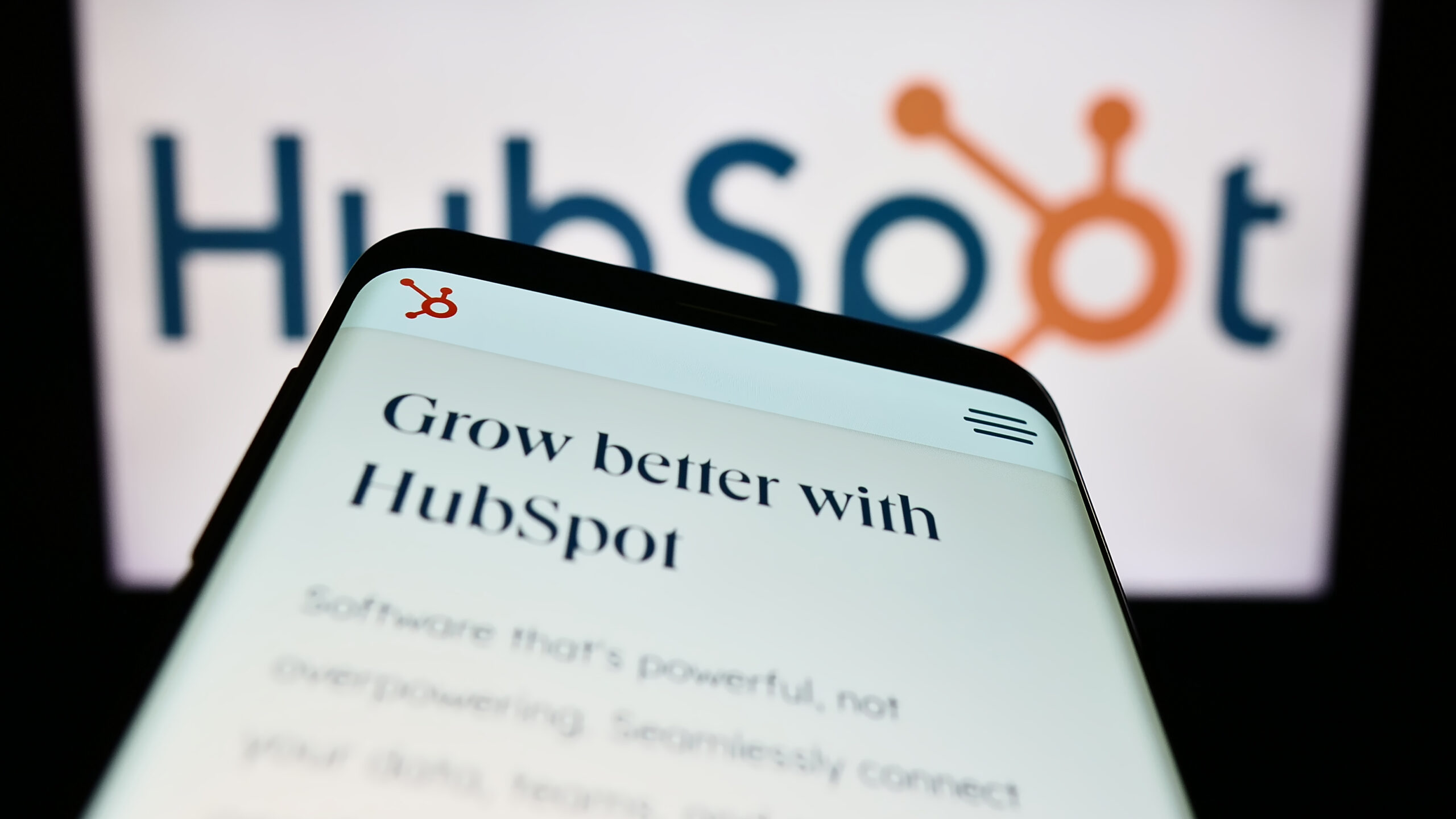 Smartphone with website of US marketing software company HubSpot Inc. on screen in front of business logo. Focus on top-left of phone display